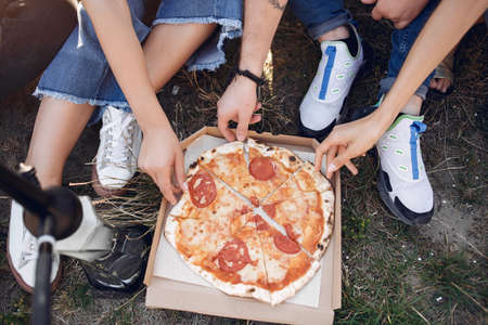 Young people eating pizza smoking shisha outsideの写真素材