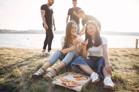 Young people eating pizza smoking hookah outsideの写真素材