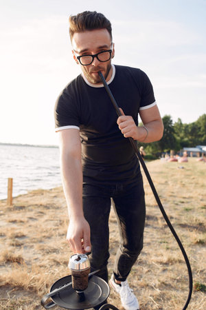 Portrait of bearded man in glasses smoking hookah