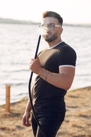 Portrait of bearded man in glasses smoking hookah