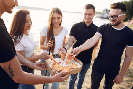 Young people eating pizza smoking hookah outsideの写真素材