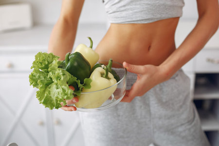 Beautiful and sporty girl in a kitchen with a vegetables