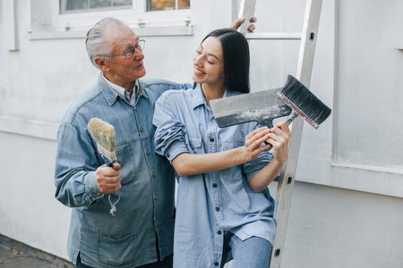 Family standing near building with repair tools