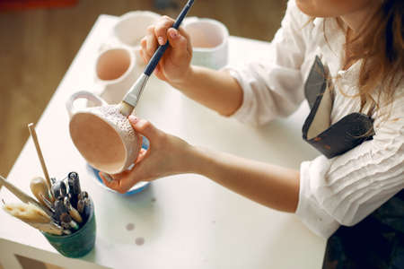 A young woman mpainting dishes in a potteryの写真素材