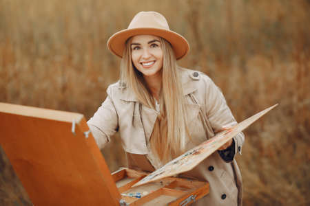 Woman in a brown coat painting in a fieldの写真素材