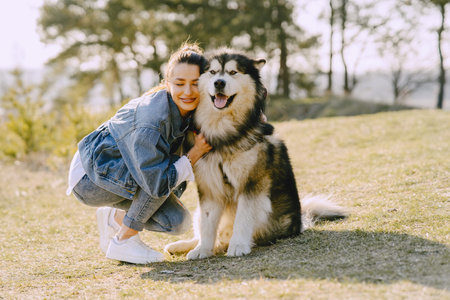 Stylish girl in a spring field with a dog