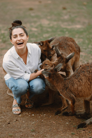 Woman in the reserve is playing with a kangaroo