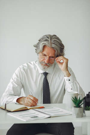 Handsome pensive mature businessman sitting in the officeの写真素材