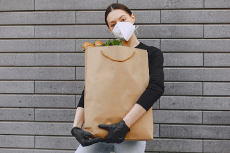 Girl in protective mask holds package with products
