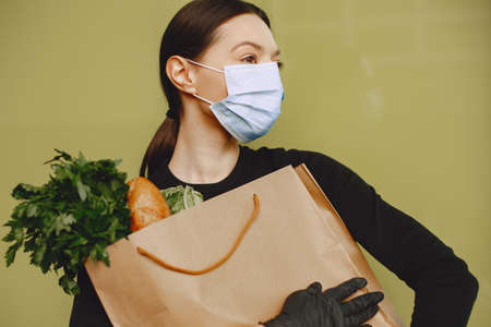 Girl in protective mask holds package with productsの写真素材