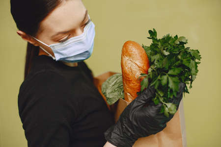 Girl in protective mask holds package with productsの写真素材