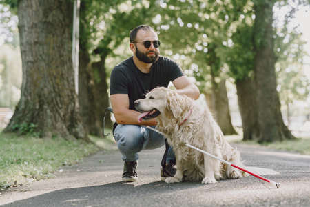 Blind man with guide dog in a summer cityの写真素材