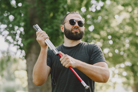 Blind young man in black sunglasses walking outdoors