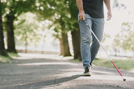 Blind young man in black sunglasses walking outdoorsの写真素材