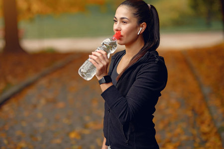 Sports girl in a black top training in a autumn park