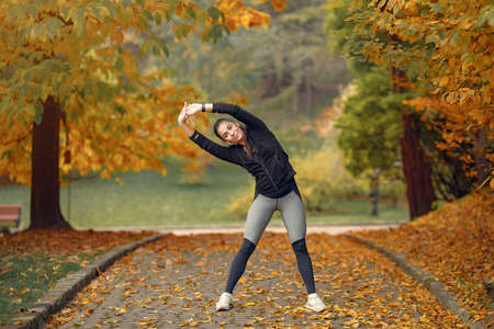 Sports girl in a black top training in a autumn parkの写真素材