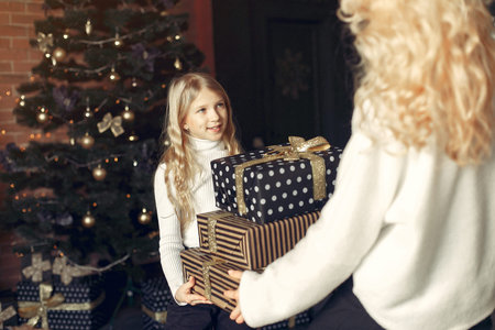 Mother with cute daughter at home near christmas tree