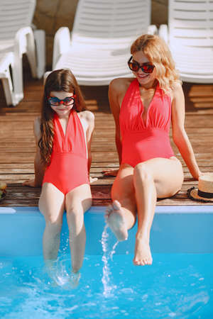 Mother and her little daughter have fun near the swimming poolの写真素材