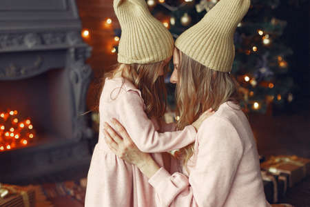 Mother with cute daughter at home near fireplaceの写真素材