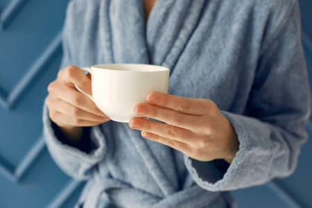 Beautiful girl standing in a studio in a blue bathrobeの写真素材