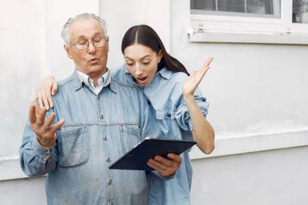 Girl teaching her grandfather how to use a tabletの写真素材