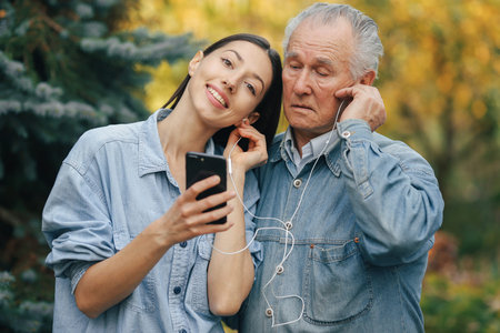 Girl teaching her grandfather how to use a phoneの写真素材