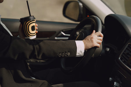 Businesswoman sitting inside a car and drinksa coffee