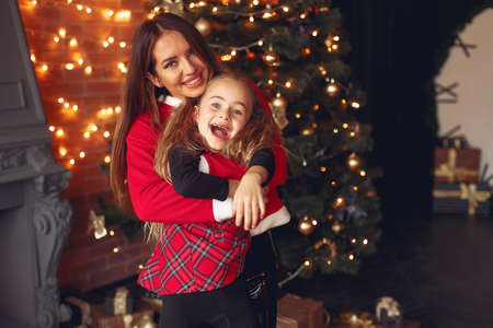 Mother with cute daughter at home near fireplaceの写真素材
