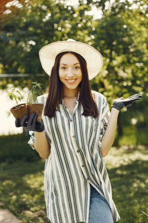 Woman in a hat holding flowerpotsの写真素材