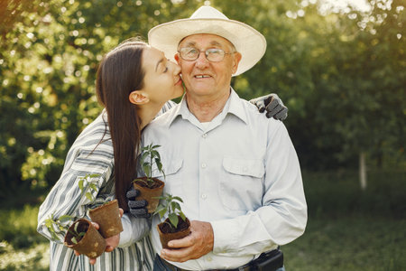 Portrait of senior man in a hat gardening with granddaugher