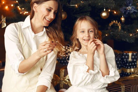 Mother with cute daughter at home near fireplaceの写真素材