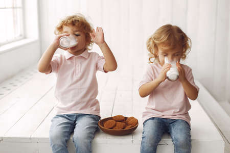 Cute children eatting cookies and drinking milkの写真素材