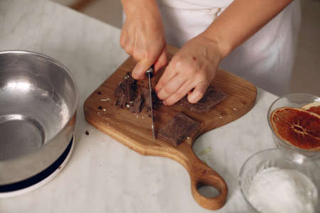 Confectioner cuts chocolate on a wooden board.の写真素材