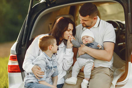 Family in a summer forest by the open trunkの写真素材