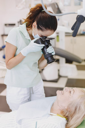 Dentist looking her old patient with tools