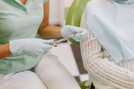 Dentist looking her old patient with toolsの写真素材