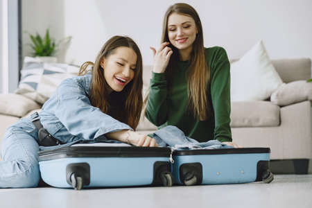 Women prepare travel suitcase at homeの写真素材
