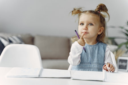 Little girl sitting on a table with booksの写真素材