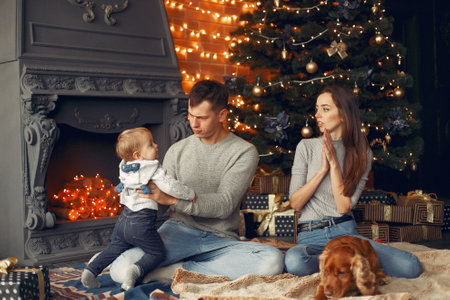 Family with cute dog at home near christmas treeの写真素材