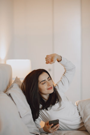 Woman in a bedroom using cellphoneの写真素材