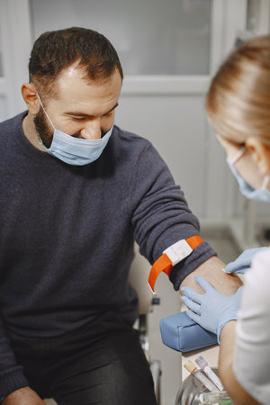 Nurse taking blood sample from patient at the doctors officeの写真素材
