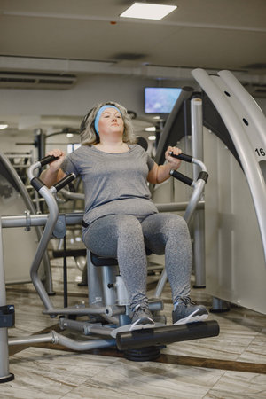 Adult fat woman doing gymnastics at the gym