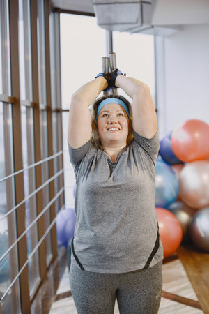 Adult fat woman doing gymnastics at the gym