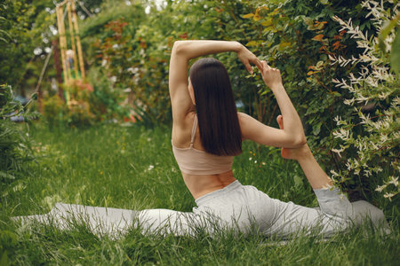 Woman practicing advanced yoga in a parkの写真素材