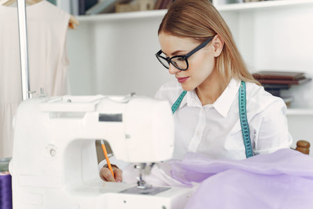Woman sitting in studio and sew cloth