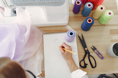 Woman sitting in studio and sew clothの写真素材