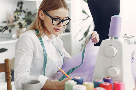 Woman sitting in studio and sew clothの写真素材