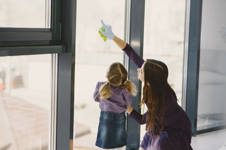 Daughter and mother cleaning window togetherの写真素材