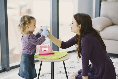 Mother with daughter playing with toy ironの写真素材