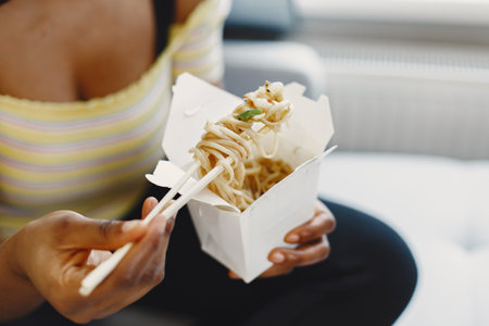 Beautiful young african american woman eating noodlesの写真素材